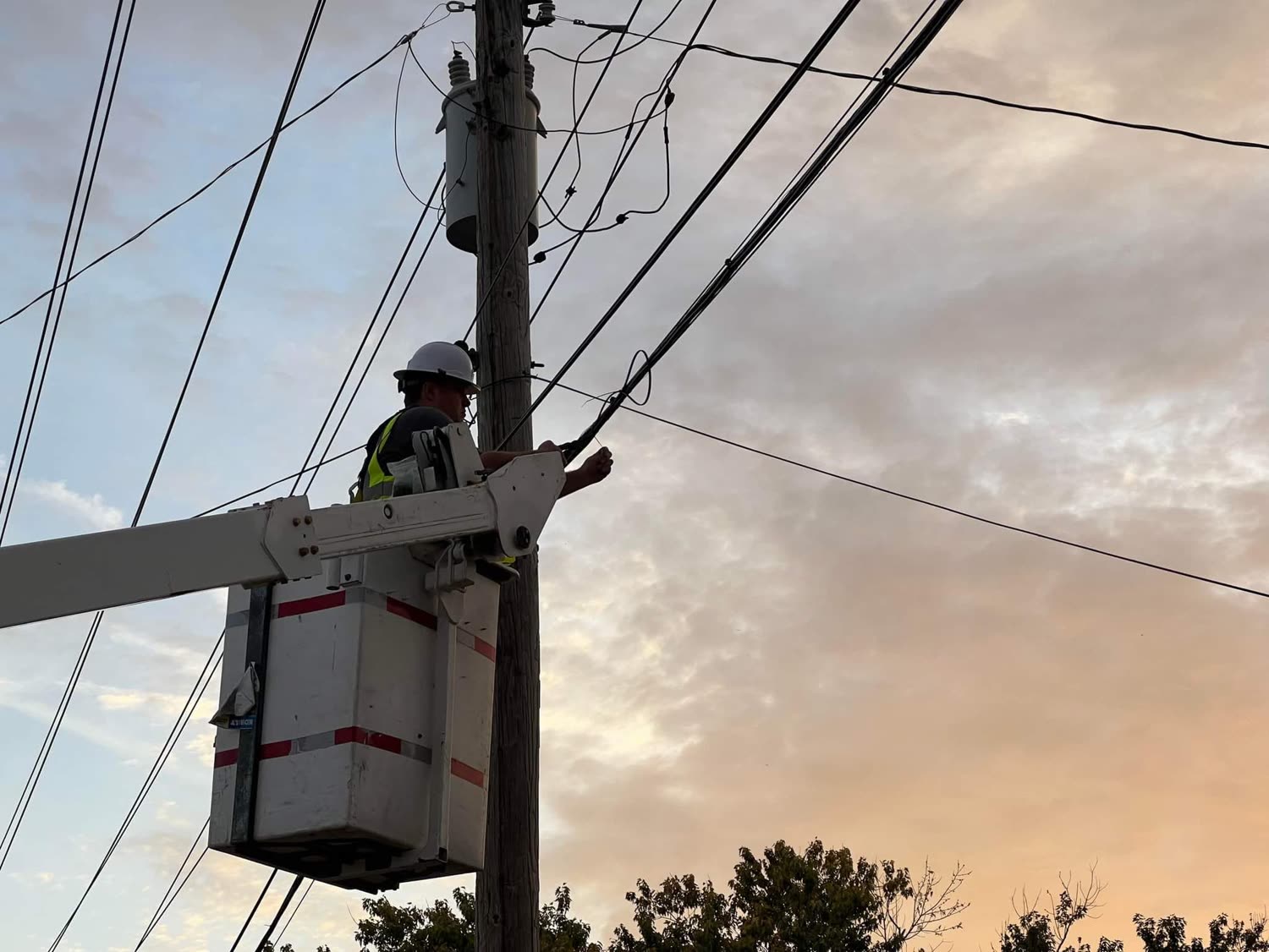A Quad State Internet technician working from a bucket truck at sunset